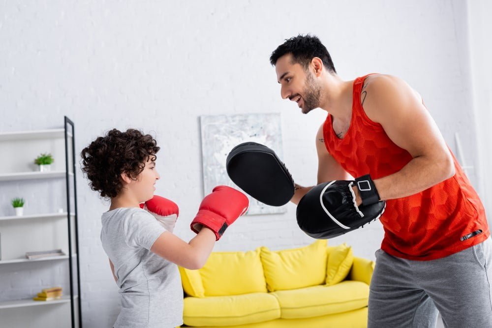 Far og søn der træner boksning i hjemmet